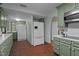 Spacious kitchen featuring sage green cabinets, brick floors, and modern appliances at 1188 Turner Rd, Creedmoor, NC 27522