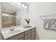 Bathroom features modern vanity with single sink, large mirror, modern lighting, and tiled shower with glass door at 1208 Wind Rose Dr, Fuquay Varina, NC 27526