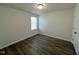 An empty bedroom features a light fixture, one window and dark wood flooring at 1208 Wind Rose Dr, Fuquay Varina, NC 27526