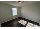 An empty bedroom features a light fixture, one window and dark wood flooring at 1208 Wind Rose Dr, Fuquay Varina, NC 27526