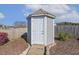 Backyard storage shed with a white door and gray siding at 1208 Wind Rose Dr, Fuquay Varina, NC 27526