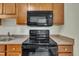 Kitchen features wood cabinets and black appliances including a microwave and stove at 1283 Schaub Dr # B, Raleigh, NC 27606