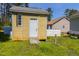 The yellow wooden shed features a single window, a white door, and a small ramp leading up to the entrance at 133 Grassy Rio Ln, Garner, NC 27529