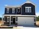 Two-story home featuring a large garage, dark siding, white trim, and black shutters against a blue sky at 144 E Victory View Ter # 66, Smithfield, NC 27577
