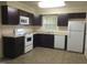 Well-lit kitchen with dark cabinets, white appliances, and granite countertops at 1505 Harth Dr, Garner, NC 27529
