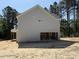 Side view of a two-story home showing the garage with an unfinished interior, gray siding, and a shingled roof at 1945 Cranes Creek Rd, Cameron, NC 28326