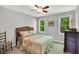 Cozy bedroom features a wicker headboard bed, ceiling fan, and two windows overlooking a beautiful green landscape at 201 Wortham Dr, Raleigh, NC 27614