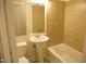 Cozy bathroom featuring tiled walls, a pedestal sink, and a bathtub for relaxation at 313 Main St, Knightdale, NC 27545
