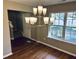 Dining room with modern chandelier, hardwood floors, and a large window with backyard view at 3316 Perkins Ridge Rd, Raleigh, NC 27610