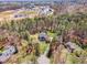 Aerial view of a multi-story brick home with a backyard in-ground pool surrounded by mature trees in a well-established neighborhood at 3601 Tartancroft Pl, Fuquay Varina, NC 27526