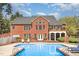Rear exterior view showcases a brick two-story home with access to a pool and elevated deck at 3601 Tartancroft Pl, Fuquay Varina, NC 27526