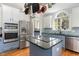 Modern kitchen with stainless steel appliances, granite countertops, and a unique pot rack above the island at 3601 Tartancroft Pl, Fuquay Varina, NC 27526