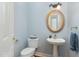 Well-lit powder room with a pedestal sink, oval mirror, and light blue walls with white trim at 3601 Tartancroft Pl, Fuquay Varina, NC 27526
