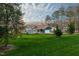 Aerial view of a charming single-story home with a well-maintained lawn surrounded by lush greenery and mature trees at 390 Lake Magnolia Way, Smithfield, NC 27577