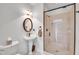 Bathroom featuring a walk-in shower, pedestal sink, decorative mirror, and soft lighting at 390 Lake Magnolia Way, Smithfield, NC 27577