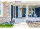 Inviting front porch with chairs and side table, stone accents, and well-maintained landscaping at 390 Lake Magnolia Way, Smithfield, NC 27577