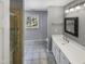 Bright bathroom with a large vanity, shower, tiled floors, window, and view to backyard at 4216 High Mountain Dr, Raleigh, NC 27603