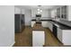 Open kitchen features modern stainless appliances, white cabinetry, a large island, and hard wood flooring at 4216 High Mountain Dr, Raleigh, NC 27603