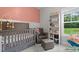 A cute Bedroom with a rocking chair, crib and a view from the window to the yard at 501 E Granville St, Dunn, NC 28334