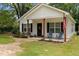Inviting front exterior featuring a quaint porch with seating, American flag, and manicured landscaping at 501 E Granville St, Dunn, NC 28334