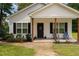 Charming front porch with wood pillars, a black door with a 
