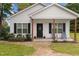 Charming front porch with black door, seating, and well-maintained landscaping and beautiful plants at 501 E Granville St, Dunn, NC 28334