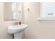 Well-lit bathroom with pedestal sink, mirror, and window providing natural light at 5800 Agrinio Way, Raleigh, NC 27603