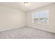 Cozy bedroom with soft carpet, neutral walls, and a bright window showcasing the outdoors at 5800 Agrinio Way, Raleigh, NC 27603