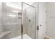 Walk-in shower featuring gray tile walls, glass door, and built-in corner seat at 65 Cordoba Dr, Franklinton, NC 27525