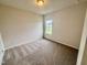 Carpeted bedroom with neutral walls and natural light streaming in from the window at 76 Commons Cir, Clayton, NC 27520
