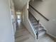 Inviting hallway with wood-look flooring and a carpeted staircase with wrought iron spindles at 76 Commons Cir, Clayton, NC 27520