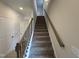 Carpeted staircase featuring stained handrail and black wrought iron spindles, leading to the upper level at 76 Commons Cir, Clayton, NC 27520