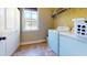 Well-lit laundry room with a white washer and dryer, tiled floor, and a window for natural light at 79 Hillgrove Dr, Willow Springs, NC 27592