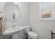 Well-lit bathroom with a modern pedestal sink and toilet with window and contemporary finishes at 8410 Zinc Autumn Path, Raleigh, NC 27615