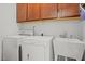 Functional laundry room with washer, dryer, utility sink, and overhead storage cabinets at 8410 Zinc Autumn Path, Raleigh, NC 27615