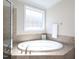 Bright bathroom featuring an oval soaking tub with tile surround and large window at 8417 Henderson Rd, Apex, NC 27539