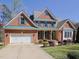 Charming two-story brick home featuring a well-manicured lawn and a spacious three car garage at 8417 Henderson Rd, Apex, NC 27539