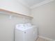 Laundry room with white washer and dryer with wooden shelf above at 8417 Henderson Rd, Apex, NC 27539