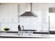 Modern kitchen with subway tile backsplash, a stainless steel range hood, and minimalist white cabinetry at 110 N Corcoran St # 2302, Durham, NC 27701