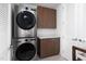 Efficient laundry room with modern stacked washer and dryer and wood cabinets with white countertop at 110 N Corcoran St # 2302, Durham, NC 27701