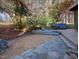 Serene backyard with stone pathway and patio seating area amidst colorful trees and lush greenery, perfect for relaxation at 111 Standing Rock Rd, Chapel Hill, NC 27516
