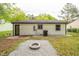 Backyard featuring a gravel fire pit area, white siding, black trim, and a small patio at 1204 Pecan Pl, Durham, NC 27704