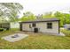 Exterior rear view of a home with a gravel firepit area, white siding, black trim, and tidy landscaping at 1204 Pecan Pl, Durham, NC 27704