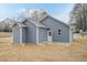 Rear exterior view of the home featuring blue siding and a small patio at 175 David Ln, Roxboro, NC 27573