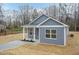 Charming single-story home with light gray siding, a front porch and green roof surrounded by dormant trees at 175 David Ln, Roxboro, NC 27573