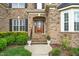 Elegant front entrance with wood door, detailed brickwork, and lush landscaping at 1808 Pattersons Mill Rd, Durham, NC 27703