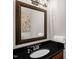 Chic powder room featuring a dark granite countertop, stylish mirror, and convenient paper towel holder at 1808 Pattersons Mill Rd, Durham, NC 27703