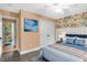 Cozy bedroom featuring a bed with blue bedding, floral wallpaper and a door leading to a colorful room at 198 Hillsdale Dr, Archer Lodge, NC 27527