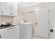 Well-lit laundry room with white appliances, white cabinets, wire rack and a white door at 198 Hillsdale Dr, Archer Lodge, NC 27527