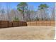 Fenced backyard with dry grass and view of trees at 2040 Water Marsh Trl, Fuquay Varina, NC 27526